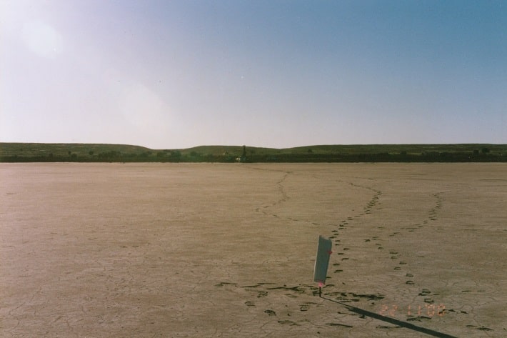 Drill rig on the edge of Hiles Lagoon in the background 
      is aiming at the peg which is located over the centre of the target 
      gravity anomaly (peg removed at completion of drilling)